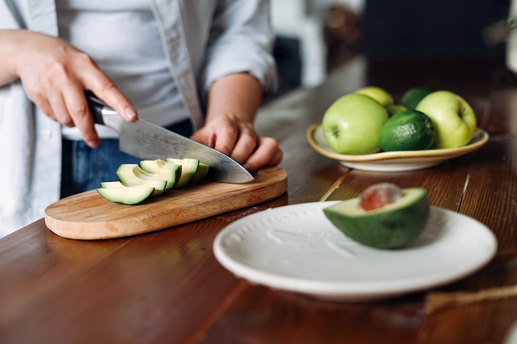Slicing ripe avocados on a brown wood cutting board