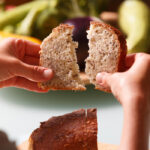 Two hands ripping a slice of fresh whole grain bread
