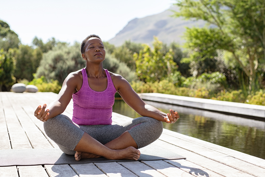 Woman sitting in a peaceful outdoor setting in a lotus pose