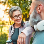 Healthy middle aged woman happily talking to middle aged man while walking outdoors