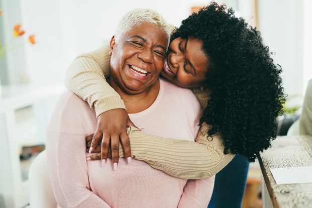 Daughter laughing and embracing happy mother from behind