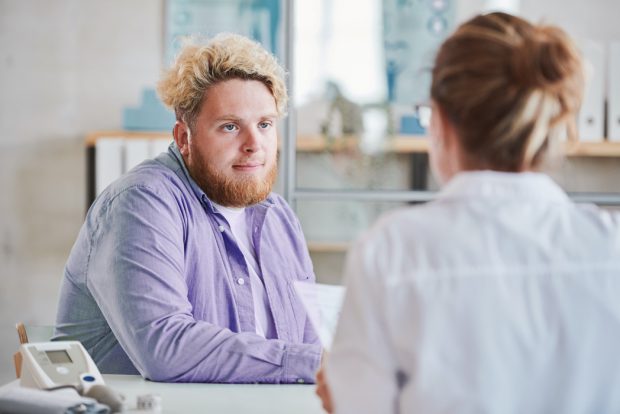 Man in purple shirt talking to a female doctor in an office setting