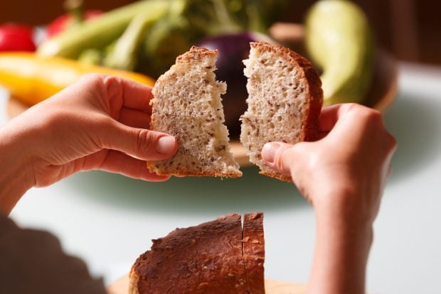 Two hands ripping a slice of fresh whole grain bread