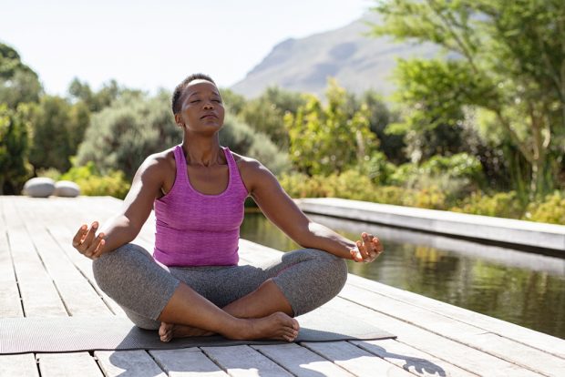 Woman sitting in a peaceful outdoor setting in a lotus pose