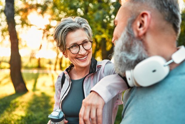 Healthy middle aged woman happily talking to middle aged man while walking outdoors
